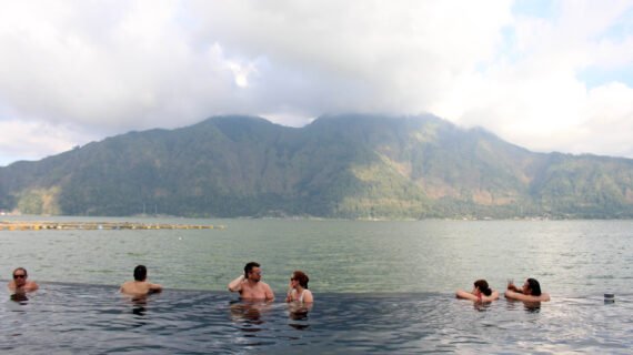 People are enjoying dipping in a hotspring (Toya Devasya), by the lake facing a mountain. Taken in Bali, May 2018.